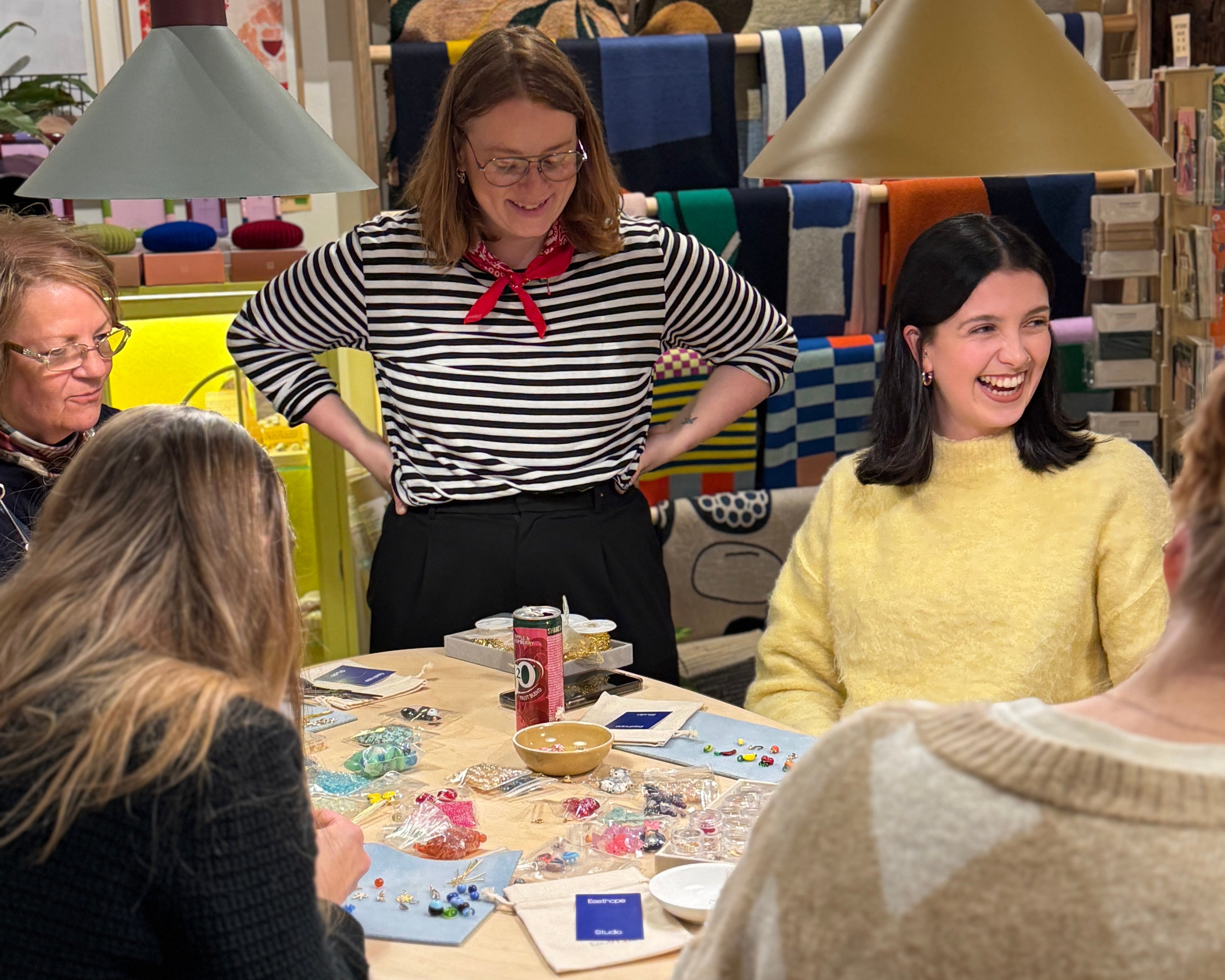 women laughing together during a creative workshop making jewellery and charm necklaces.